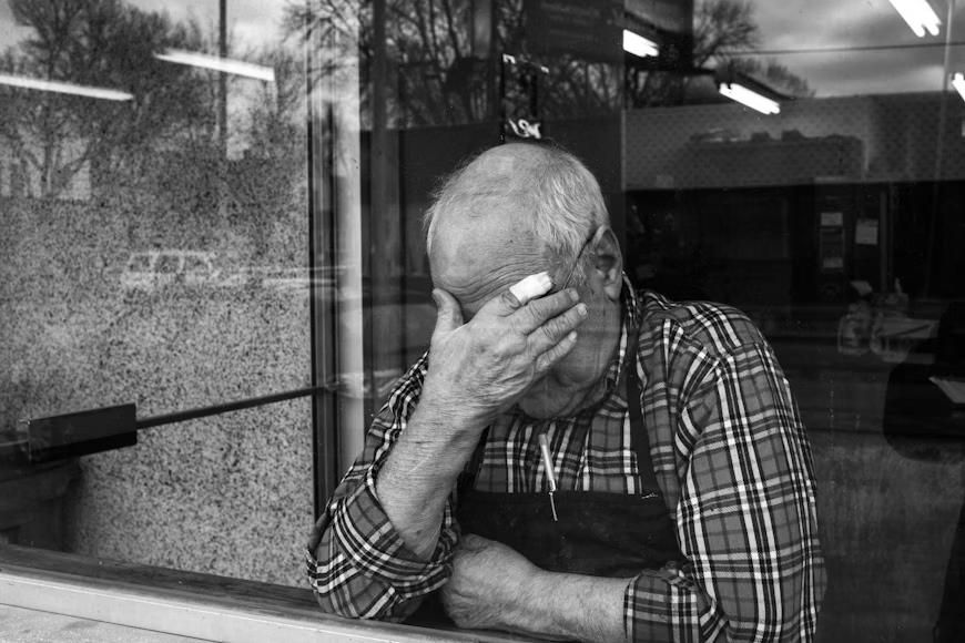 Elderly man using a cold compress for headaches seniors face