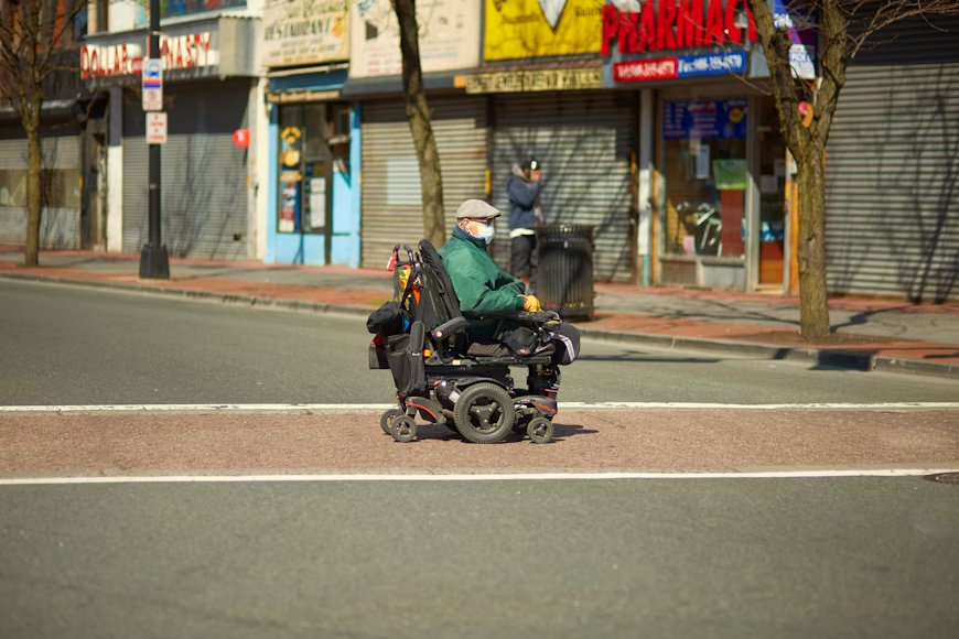 Senior on wheelchair crossing the road during summer activities on a sunny day