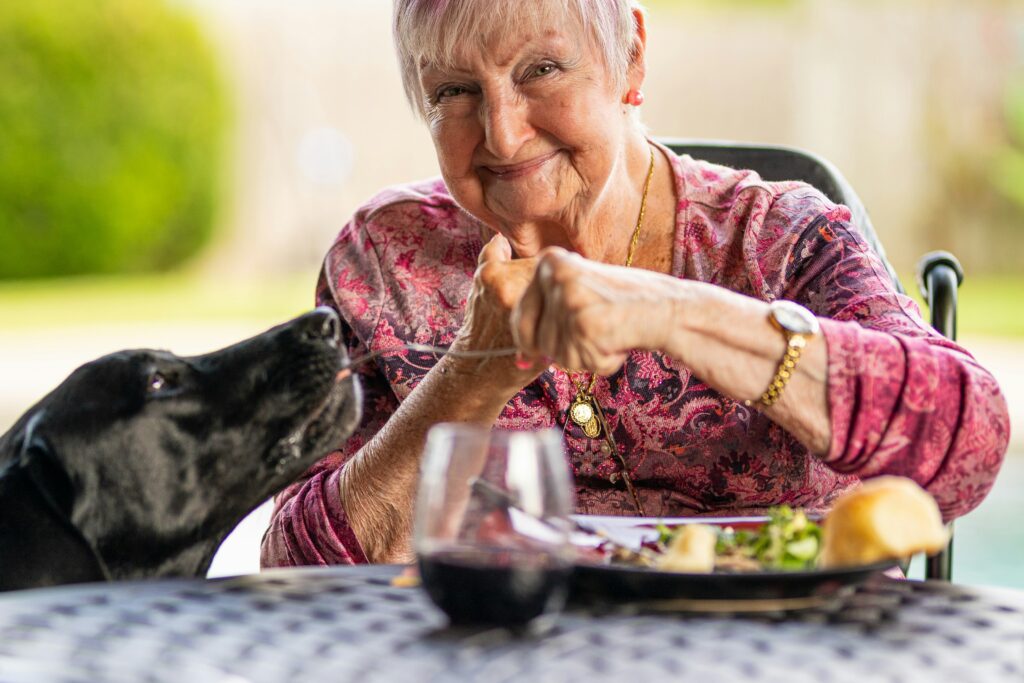 Senior woman smiling during pet therapy session with a golden retriever.