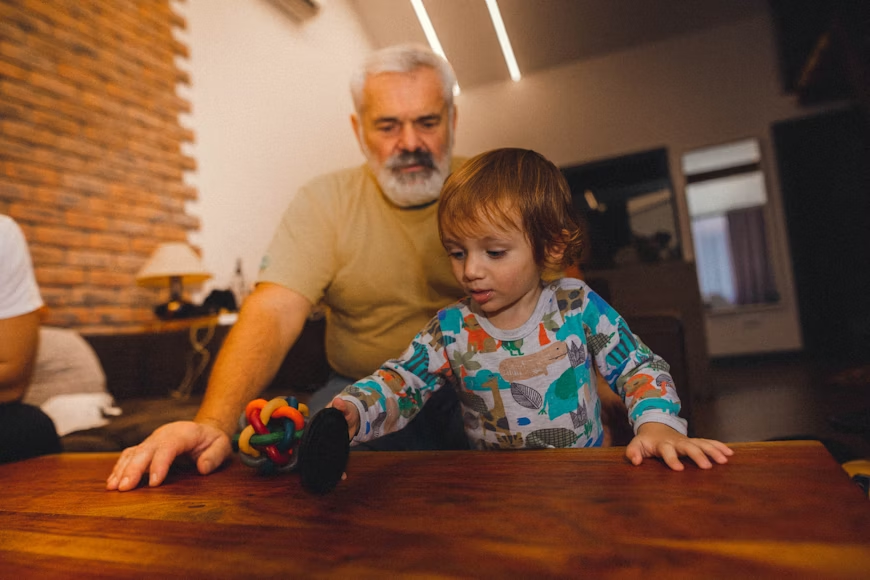Grandfather reading a book with his grandson as part of intergenerational activities