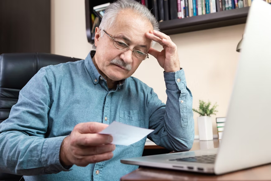 elderly person tracking living expenses on laptop