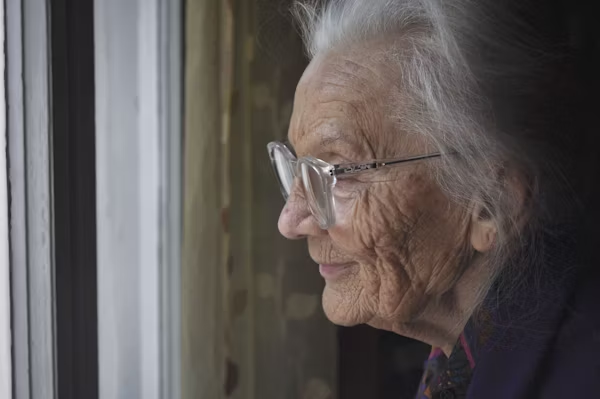 Senior woman with low vision reading a large-print book at home