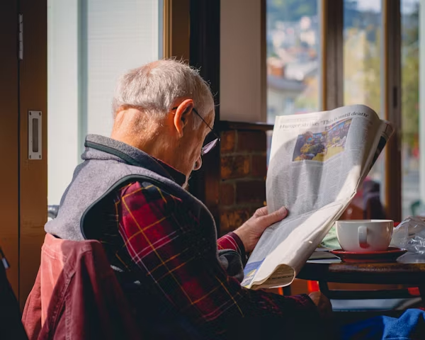 Elderly man smiling while walking safely with caregiver support.