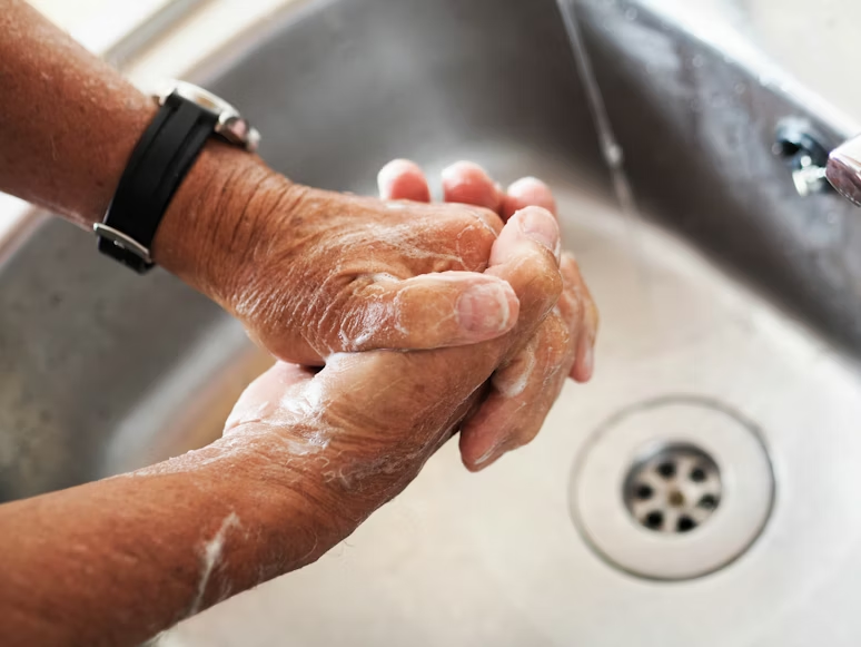 Caregiver demonstrating proper handwashing steps for senior safety