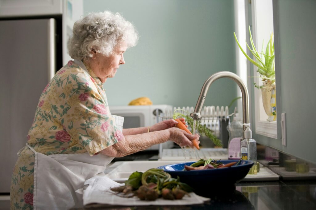 Caregiver helping senior drink water at home to support senior hydration