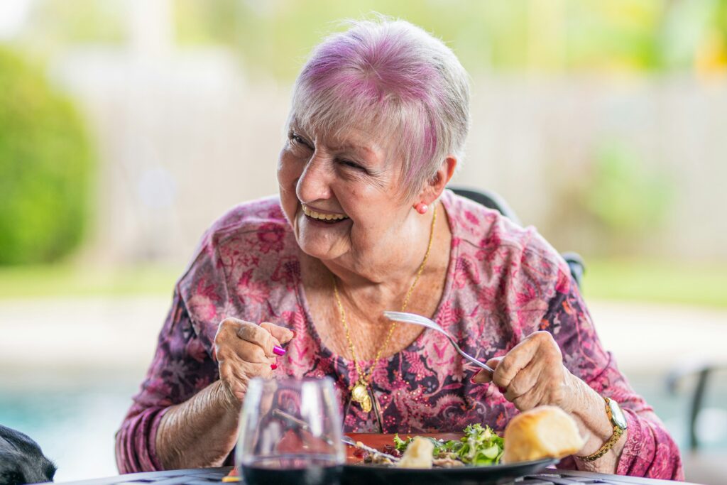A senior woman eating a meal at home, highlighting daily nutritional care and signs elderly parent needs help.