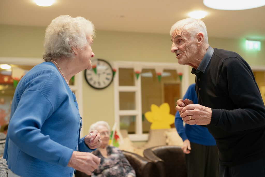 Two senior friends sitting together, smiling and enjoying each other's company