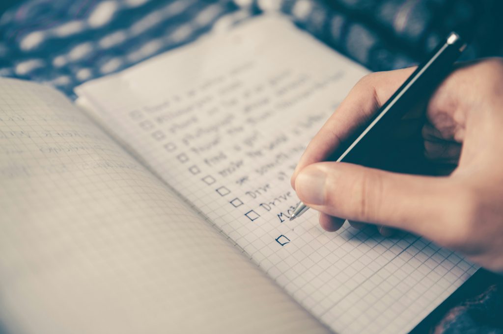Primary Alt Text:

Close-up of a hand with a pen checking off a checklist in a notebook while evaluating home care services for a family member.