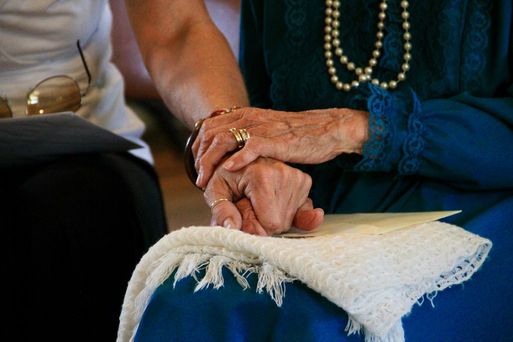 Elderly widow sharing tea with a caring companion, illustrating companionship for seniors living alone