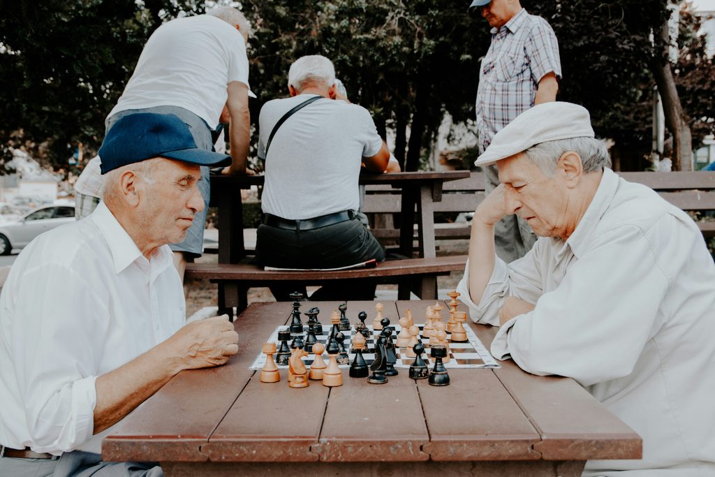 Senior man and companion caregiver playing chess at a kitchen table in an Indianapolis home